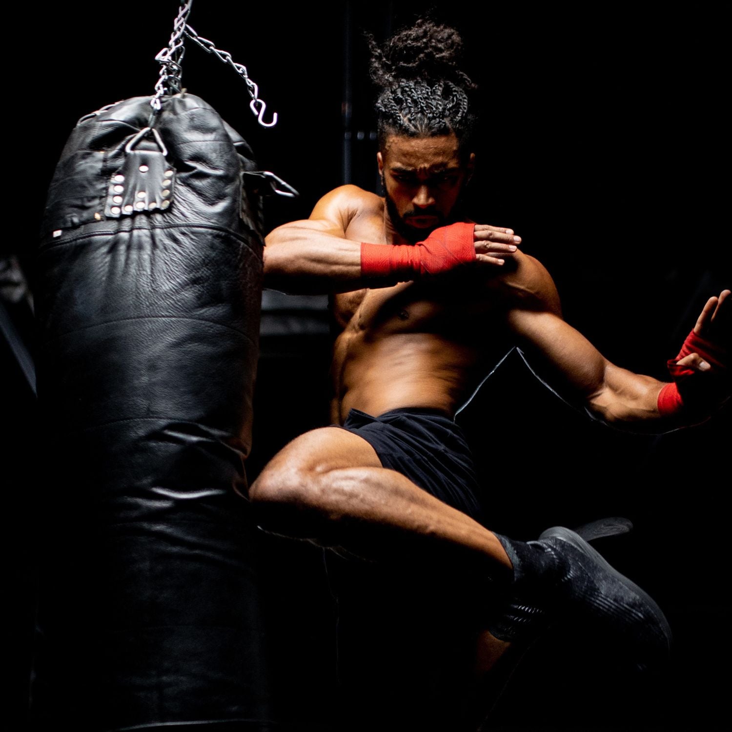 Athlete kicking a heavy bag with their knee showing the strength and resilience of the product