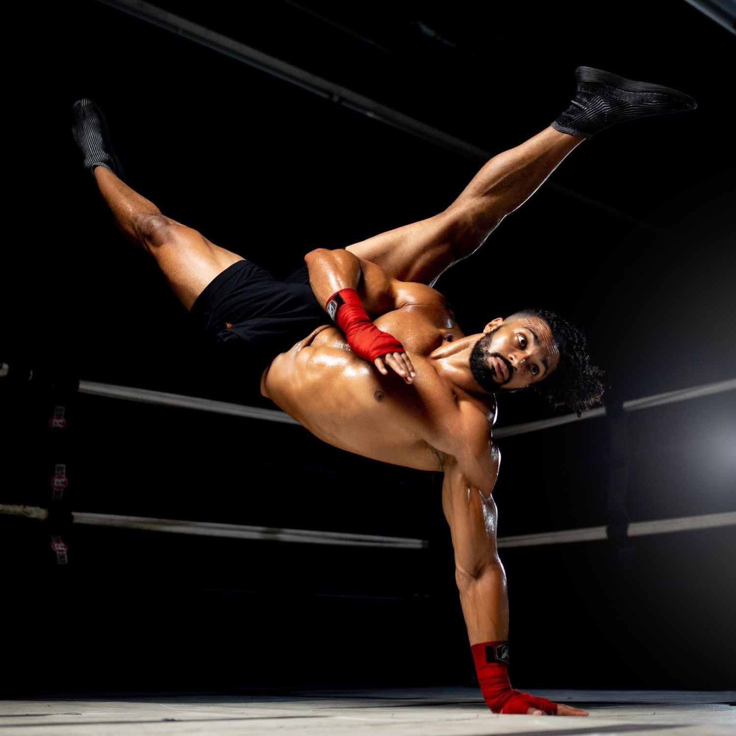 A Fitness athlete performing an acrobatic handstand in a boxing ring