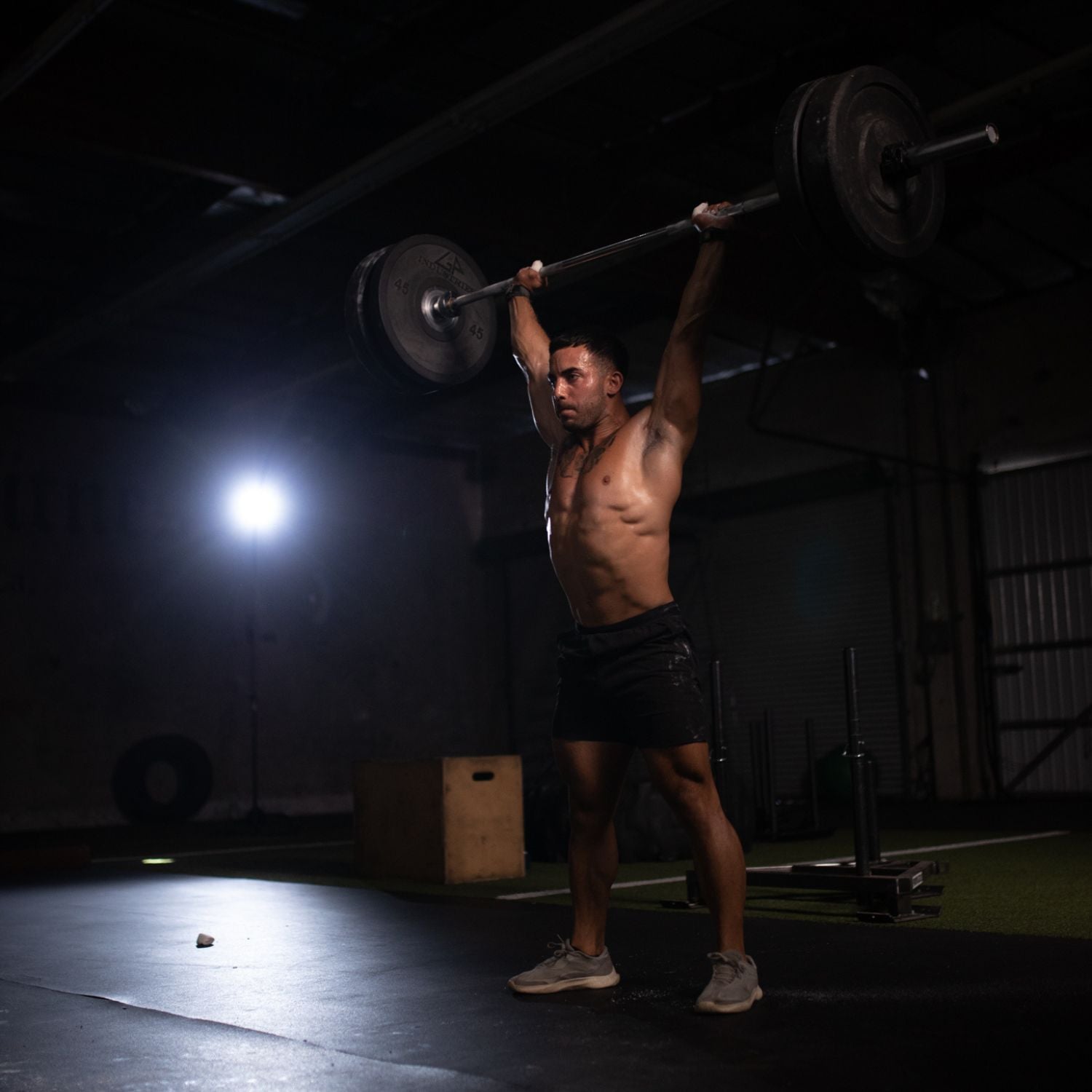 A fit athlete performing an overhead press with heavy weight on an olympic barbell after eating a liverking bar