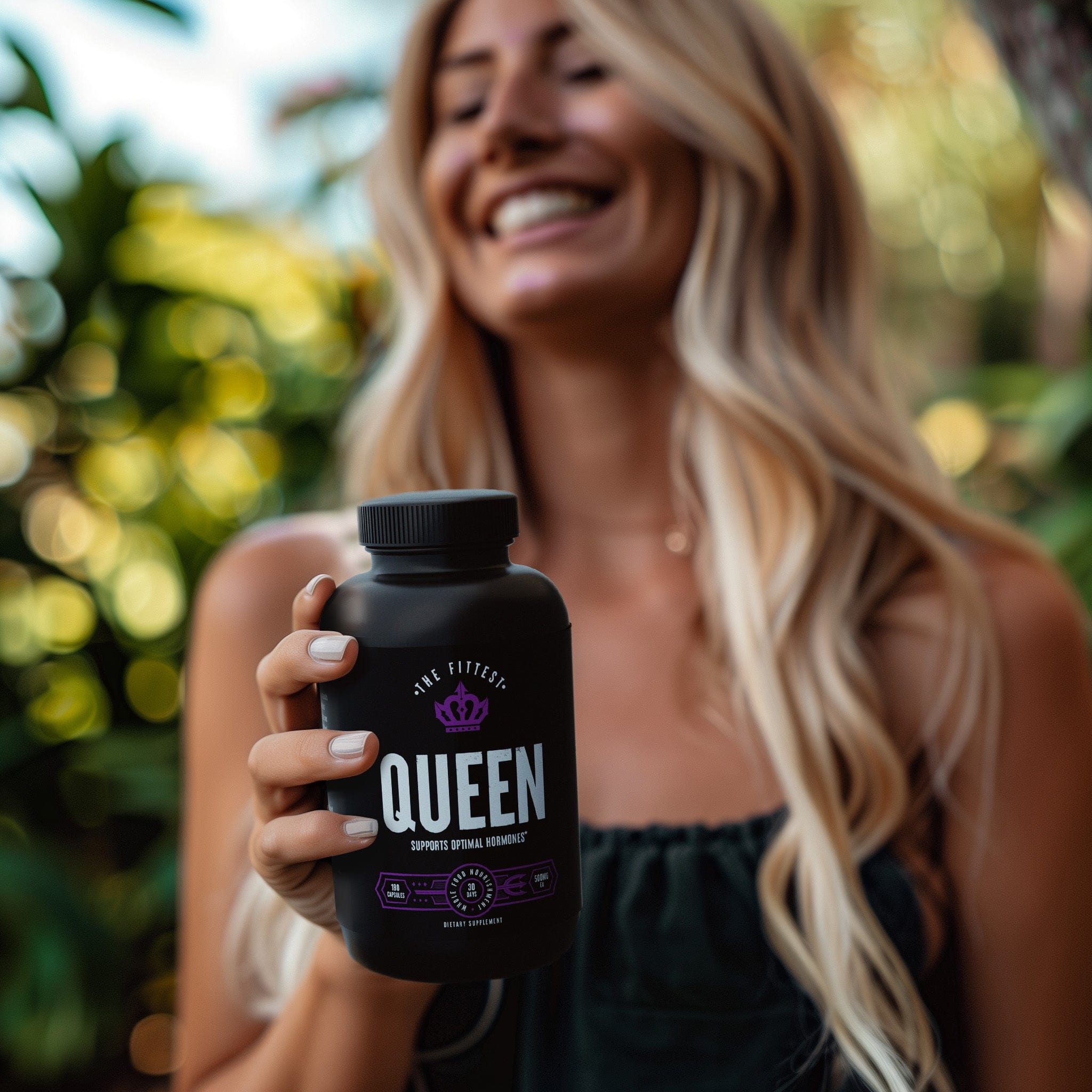 A fit woman holding a bottle of Queen out for the camera