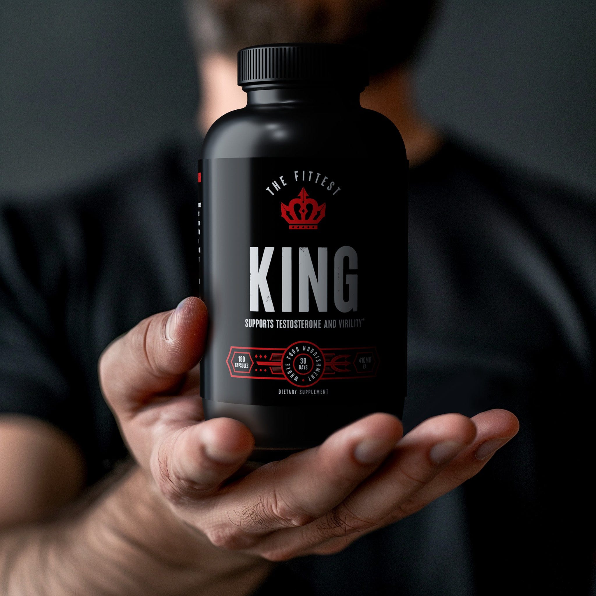 Fit man in a black shirt holding out his hand presenting a bottle of King in it 